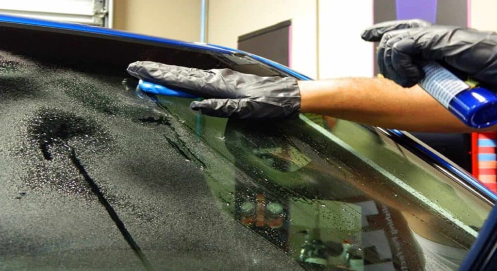 A clay bar is pulled across a windshield to remove impurities.